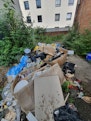 piles of rubbish outside tall buildings